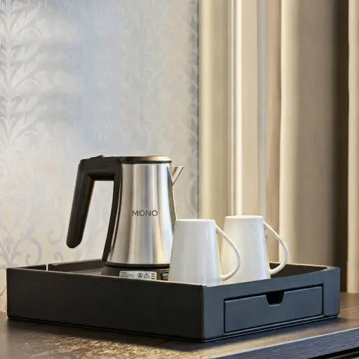 Melamine Welcome Tray with Capsule Recesses [1050] — WTR-1050 — A welcome tray in a PU-leather look or melamine, suited to both a coffee machine and a kettle, with an integrated kettle base and cable cut-out. A pull-out drawer holds six espresso capsules plus three compartments for teabags, sugar sticks or spoons. Measures 35.2x52x8.5cm, finished in black.